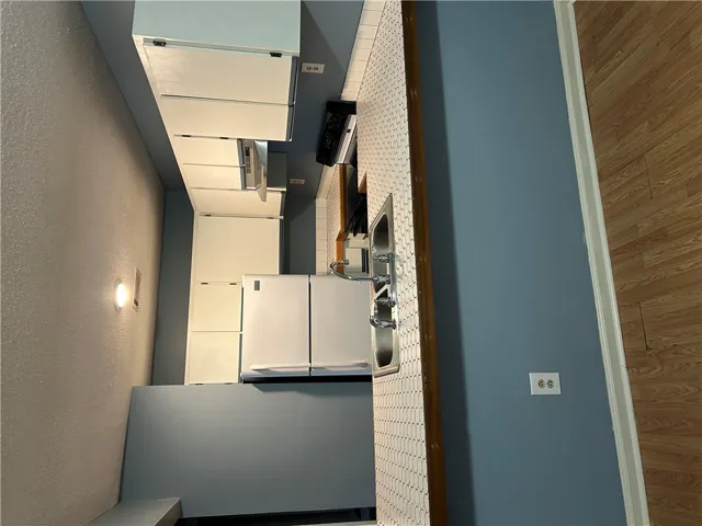 A functional kitchen layout features classic tile countertops and durable wood laminate flooring.