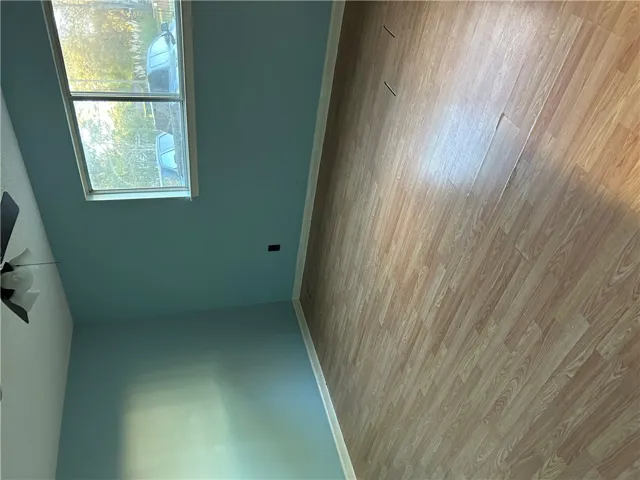 Hardwood floors and a large window create a serene atmosphere in this bedroom.
