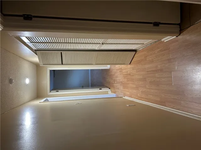 Smooth wood-look flooring guides the way down a functional, well-lit hallway with built-in storage closets.