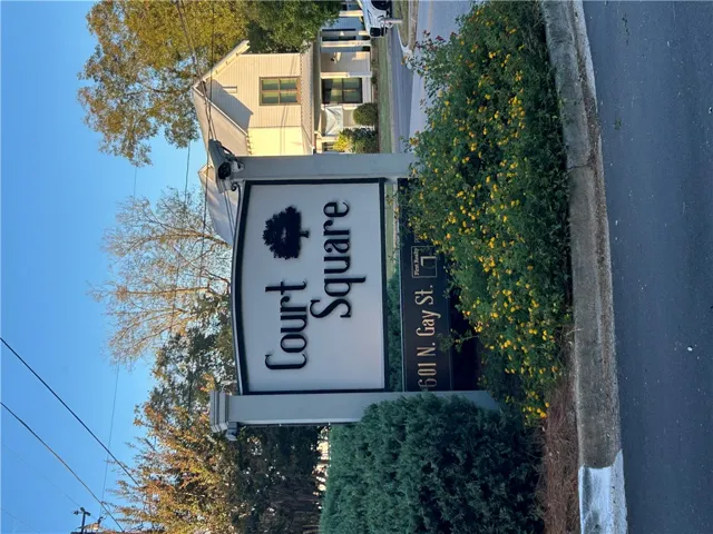A prominent neighborhood entry sign anchors the landscaped corner of this residential street.