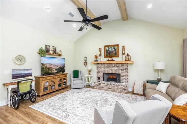 Vaulted ceilings with exposed wood beams hover over a handsome brick fireplace and wood floors.