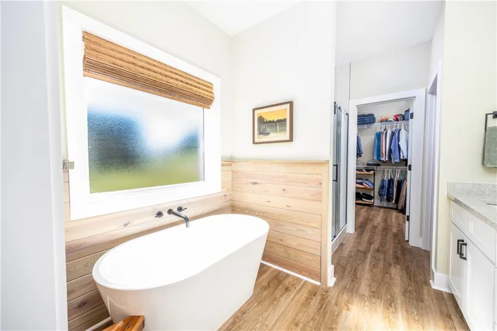 Warm wood wainscoting and a freestanding soaking tub create a spa-like master bathroom retreat.