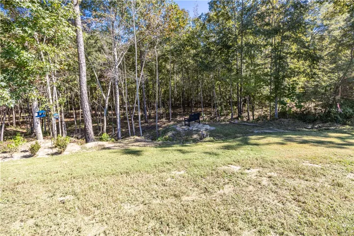 Mature trees frame a peaceful grassy clearing, creating a private woodland backdrop.