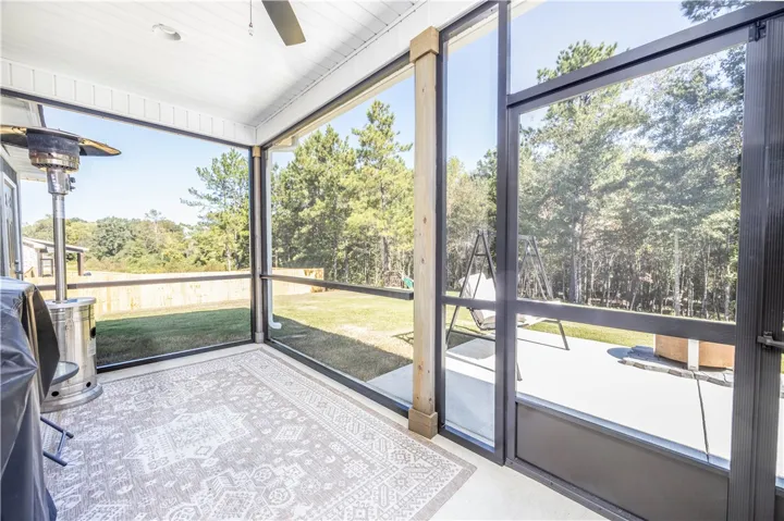 Floor-to-ceiling screens enclose a versatile outdoor living area overlooking a lush backyard.