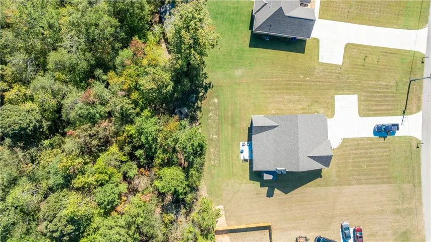 An aerial perspective showcases the home situated alongside a serene wooded border.