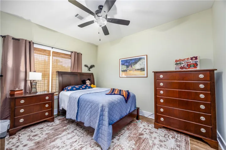 Natural light streams through wood-framed windows into a comfortable bedroom with hardwood flooring.