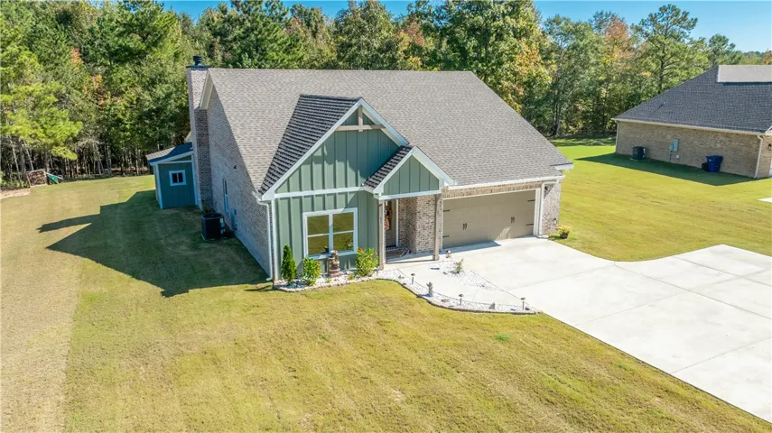 Green vertical siding and classic brickwork define this modern home with a spacious concrete driveway.