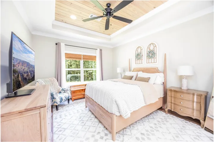 An elegant tray ceiling with natural wood accents anchors this inviting bedroom.