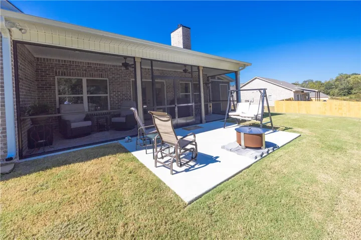 A concrete patio and screened porch extend the living space into the grassy backyard.