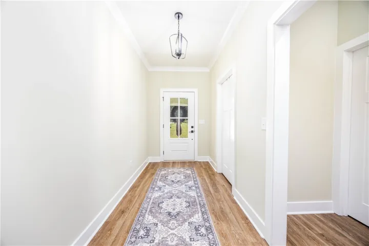 A welcoming entryway with classic crown molding and warm wood flooring leading to the main living areas.