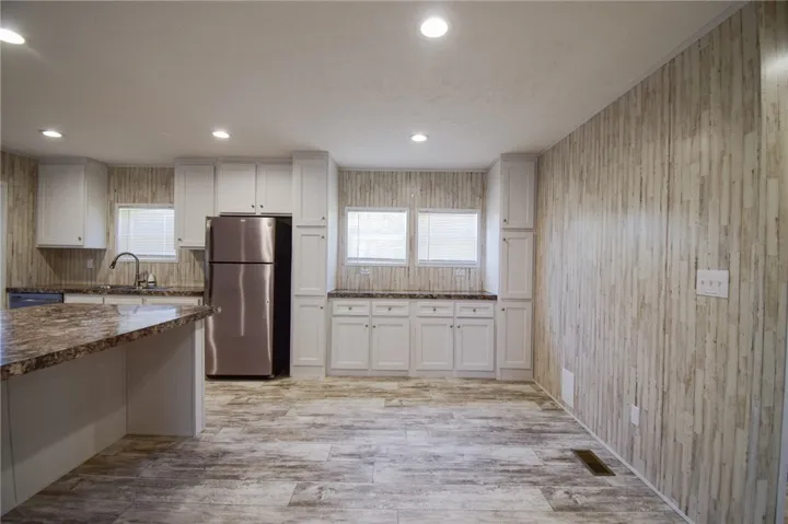 Gleaming stone countertops and crisp white cabinetry complement the textured walls and rustic flooring.