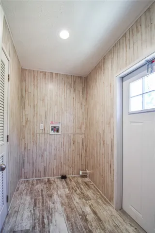 A dedicated utility space features textured wood-look flooring and rustic wall paneling.
