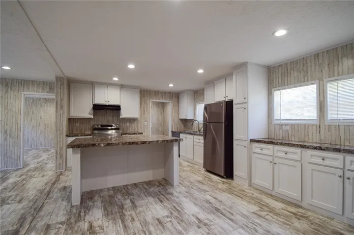 An open kitchen showcases textured walls, recessed lighting, and a central prep island.