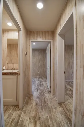 A well-lit central hallway showcases rustic wood-look plank flooring and textured wall paneling.