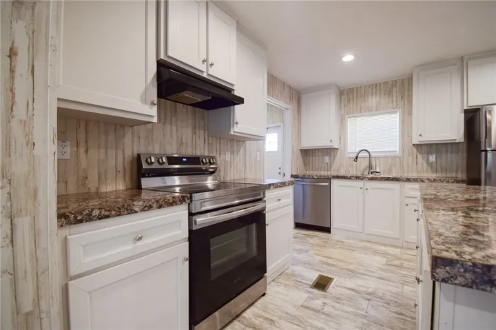 Richly patterned countertops complement crisp cabinetry and wood-look flooring in this updated kitchen.