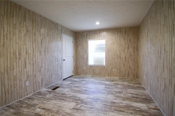 A versatile secondary room showcases textured wall paneling and durable wood-look flooring.