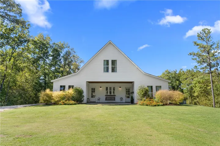 A classic white facade sits nestled among mature trees on a sprawling green lawn.