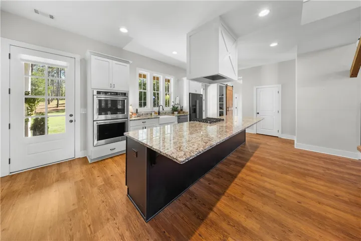 Rich hardwood floors anchor a modern culinary space highlighted by a massive granite-topped prep island.