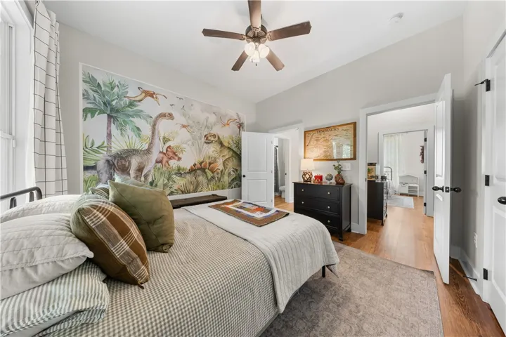 Gleaming hardwood floors run through a comfortable bedroom featuring high ceilings and classical trim.