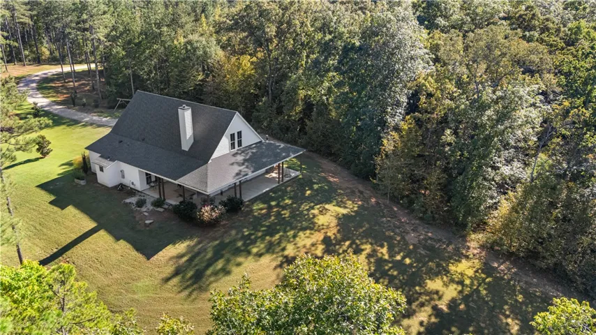 Mature woodlands frame a classic gabled residence, creating a private forest retreat.