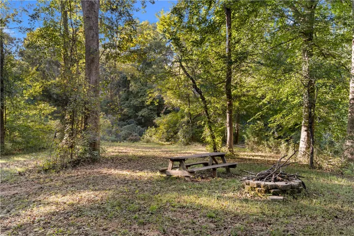 Mature trees frame a peaceful clearing complete with a built-in stone fire pit.