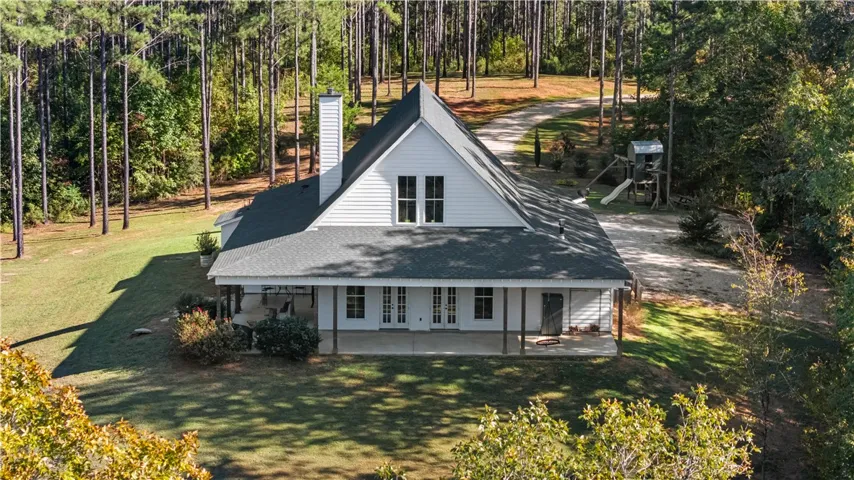 Towering pines frame this classic gabled home featuring an expansive covered porch and private yard.