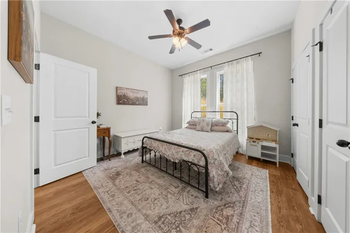 Rich hardwood flooring and tall windows create a warm, inviting atmosphere in this serene bedroom.