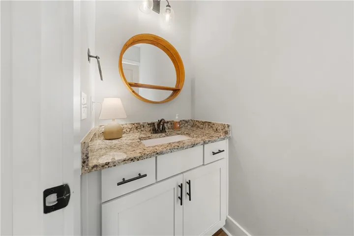 A well-appointed powder room highlights a classic single vanity topped with polished stone counters.
