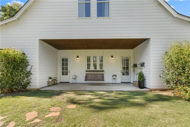 A deep covered back porch sits beneath a warm wood-toned ceiling over concrete flooring.