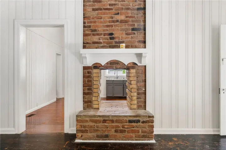 A historic double-sided brick fireplace connects interior spaces while showcasing original wood floors.