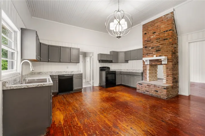 Rich hardwood flooring complements a historic brick fireplace and wood-paneled ceilings.