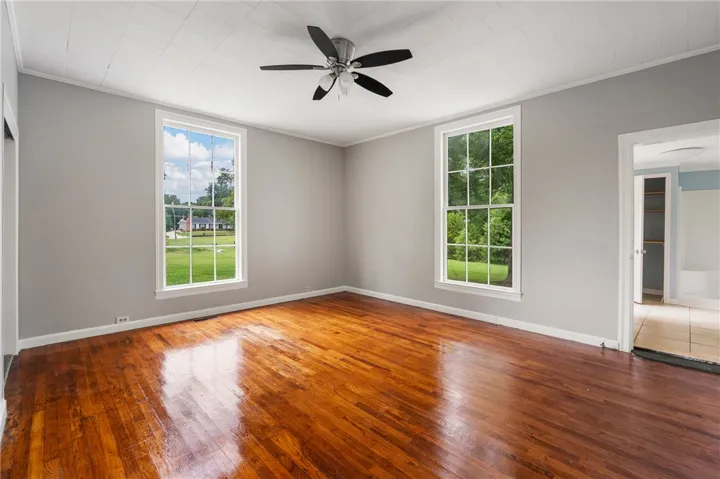 Rich hardwood floors and oversized windows define this airy, light-filled bedroom space.