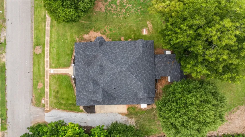 An aerial perspective shows the detailed shingle roof structure surrounded by mature trees and lawns.