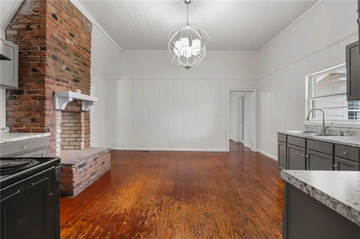 Rich hardwood floors anchor this open space featuring a classic brick fireplace and beadboard ceiling.