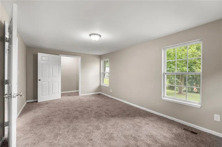 Plush wall-to-wall carpeting and multiple windows framing leafy views define this versatile space.