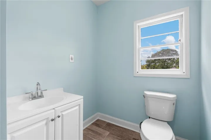 A single window draws natural light into this minimalist powder room featuring tile flooring.