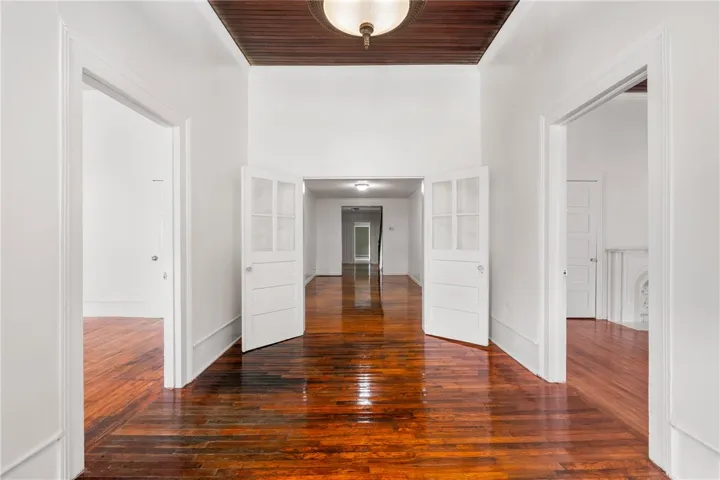 Gleaming hardwood floors and wood-paneled ceilings define this elegant, light-filled central hallway.