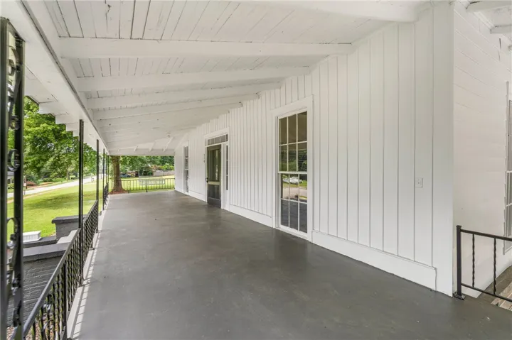 An expansive covered porch features classic board and batten siding alongside a beamed ceiling.