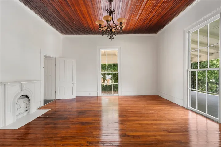 Warm hardwood floors complement a rich beadboard ceiling and an elegant decorative fireplace.
