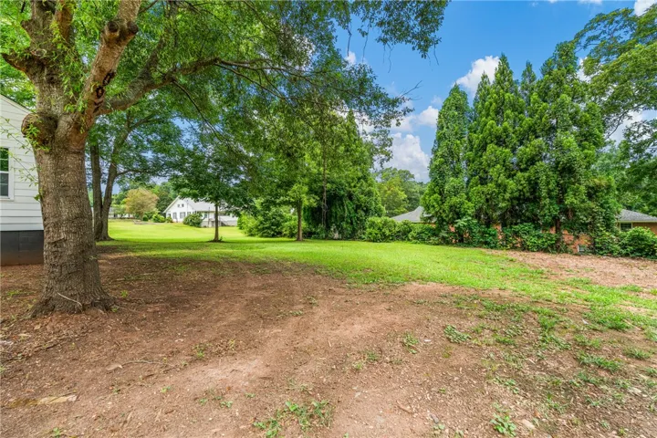 Mature trees shade a spacious green lawn, offering a serene outdoor setting.