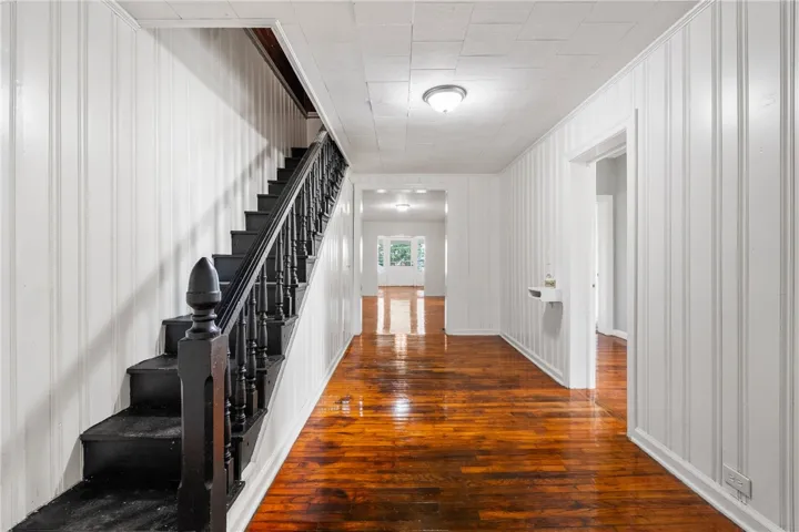 Polished hardwood floors and vertical paneling line this classic central hallway.