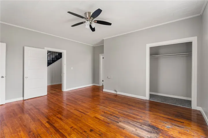 Rich hardwood flooring anchors this versatile space featuring neutral walls and an open closet design.