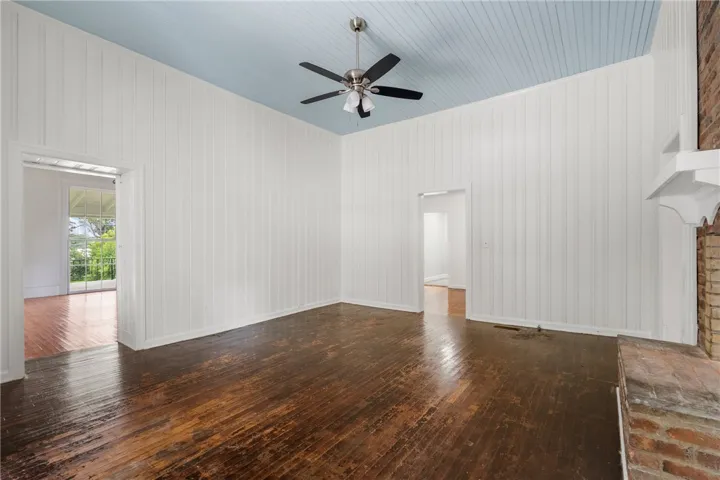Weathered wood floors pair with high panelled walls and a colored beadboard ceiling.