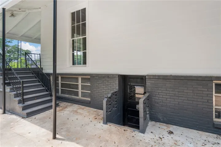 A private basement entrance steps down alongside the sturdy concrete patio and brick foundation wall.
