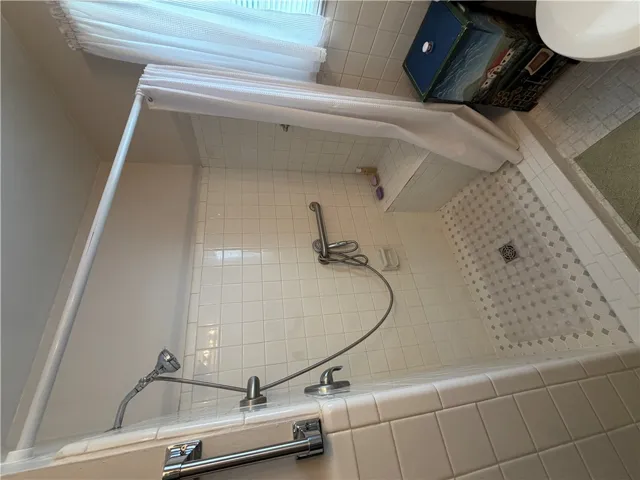 A classic tiled walk-in shower features built-in seating and chrome fixtures.