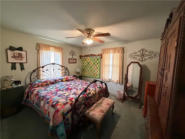 Double windows invite natural light into this cozy bedroom with wall-to-wall carpeting.