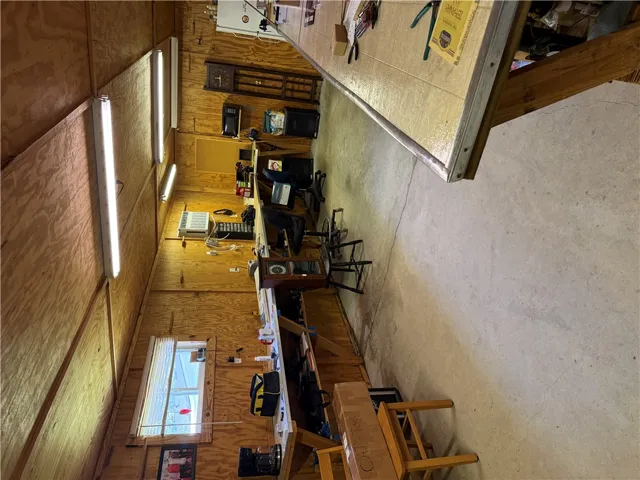 A spacious workshop provides ample counter space alongside wood walls and concrete flooring.