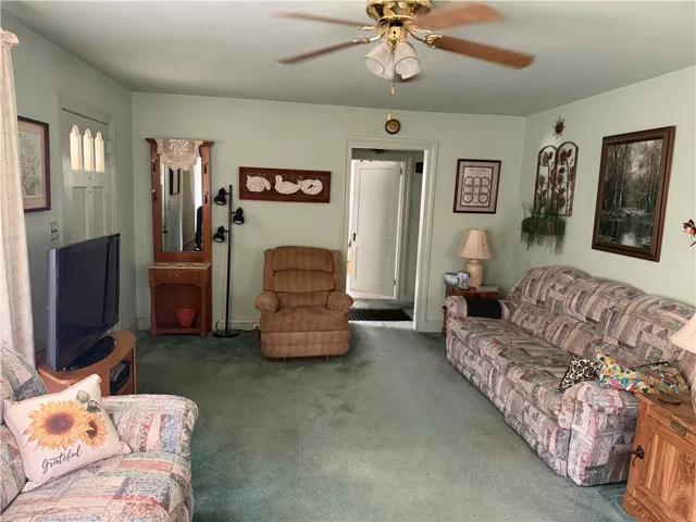 A spacious living area features soft carpeting and classic wooden doorframes leading to adjacent rooms.