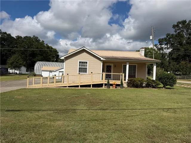 Classic siding exterior with an expansive wooden accessibility ramp leading to a covered front porch.
