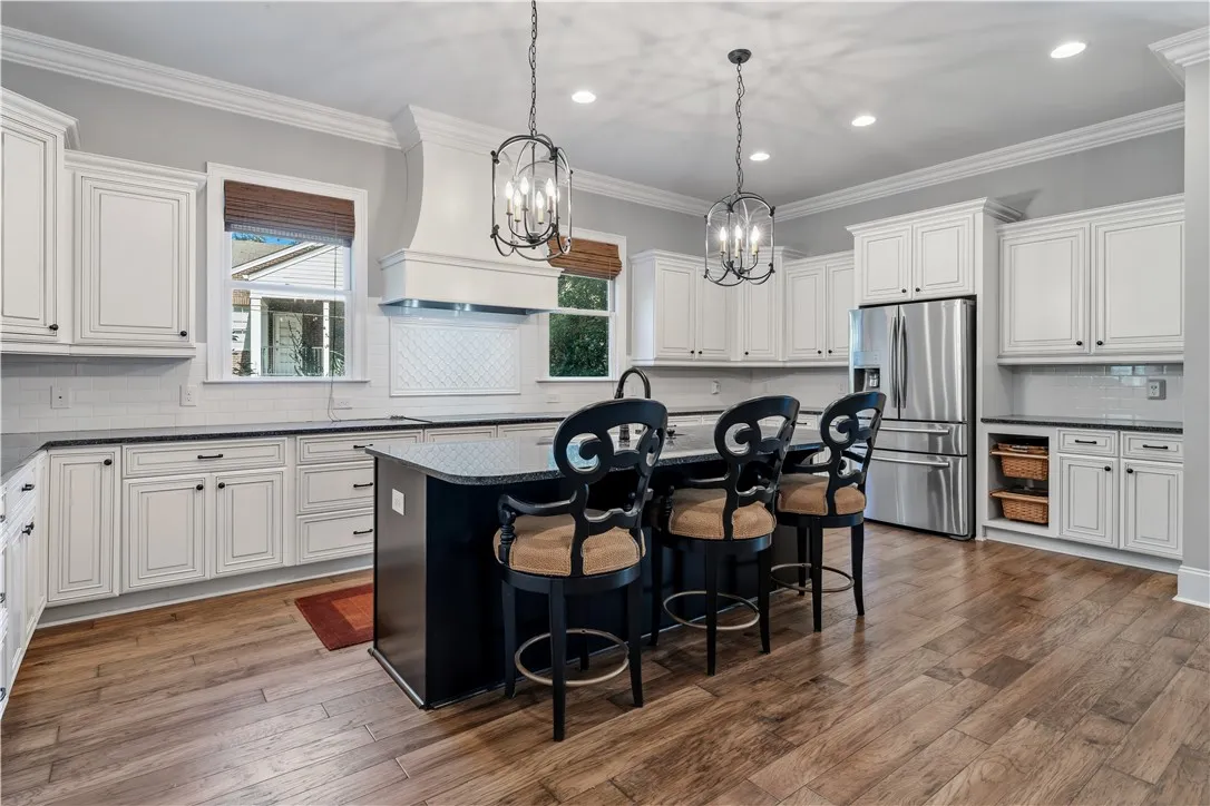 Gleaming hardwood floors run through a spacious culinary workspace featuring a center island and custom cabinetry.